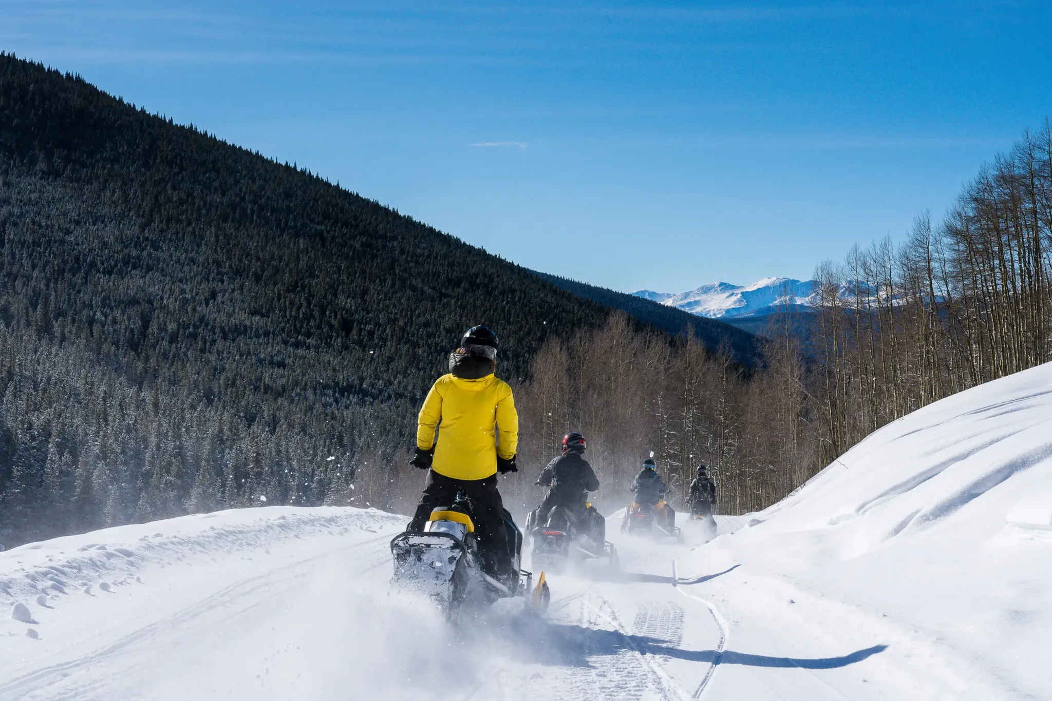 Group of snowmobilers on guided tour through forested mountains near Breckenridge Colorado
